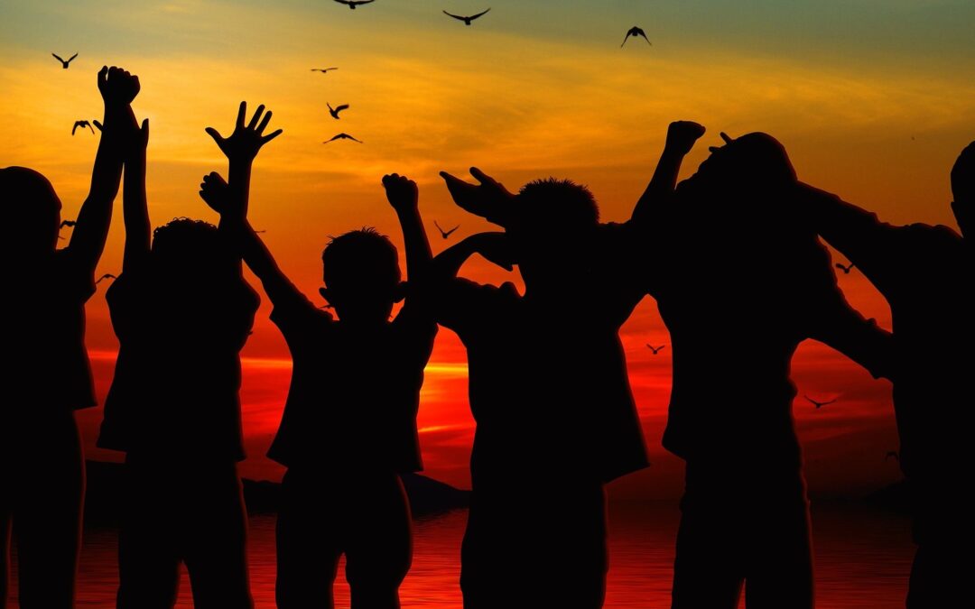 Photo of happy children cheering on a beach as the sun rises.